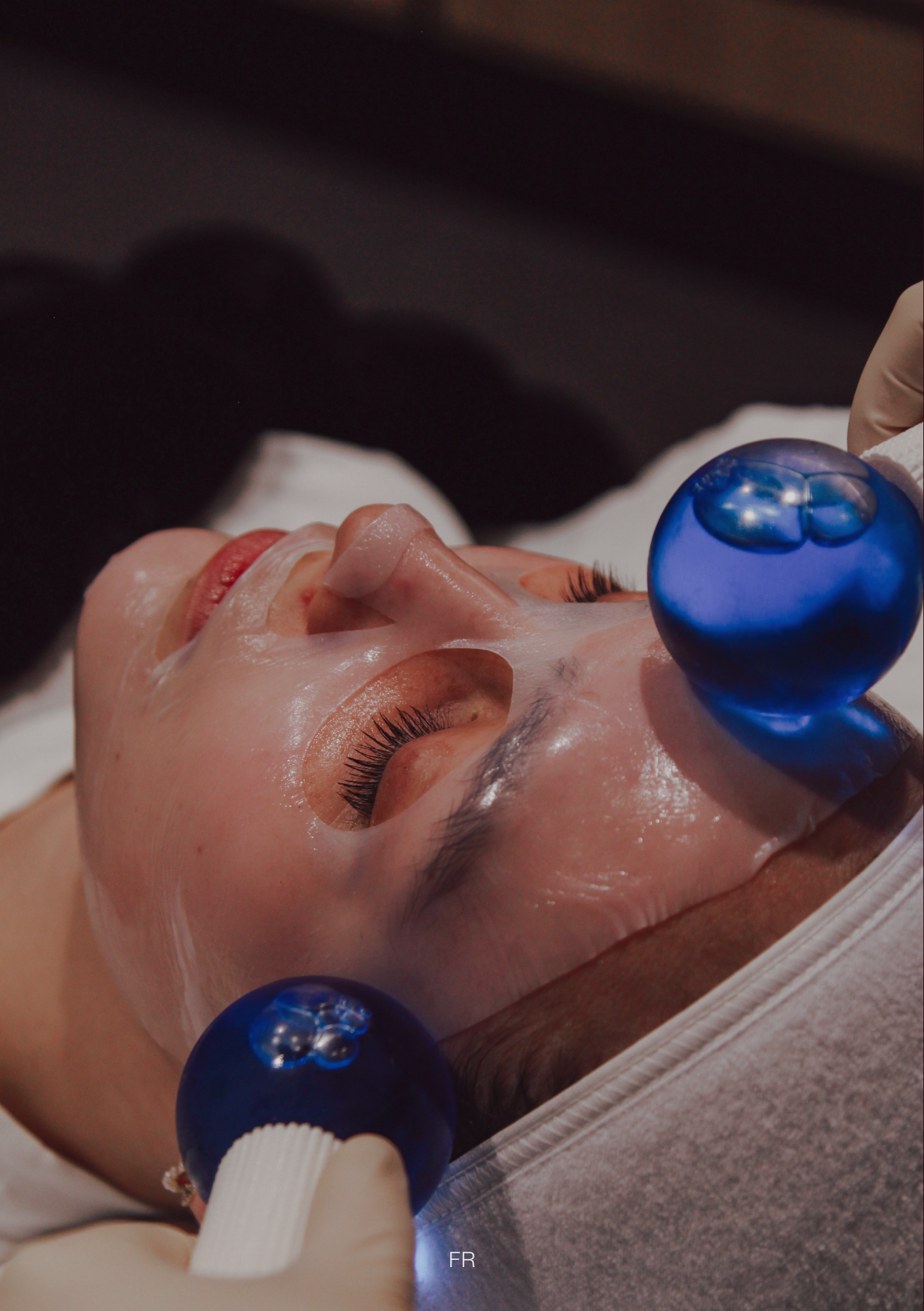 Client enjoying Flawless Rejuvenation’s Spring Skin Special facial with cooling globe massage over a hydrating sheet mask at the Hampton clinic.